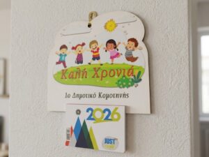 Επιτοίχιο ξύλινο ημερολόγιο με παιδιά και ευχή Καλή Χρονιά, κρεμασμένο σε τοίχο, 2026